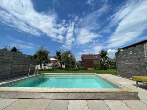 Immagine con piscina in primo piano e cielo blu con nuvole