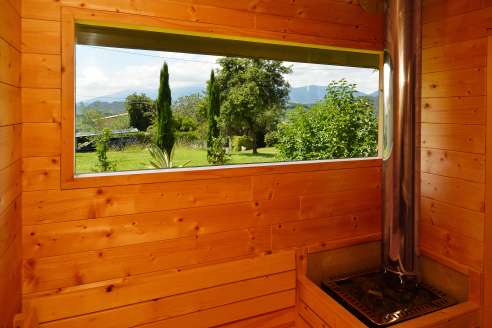 Foto scattata dall'interno della sauna con vista sul giardino e sulle colline del Prosecco