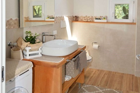 Immagine dall'interno del bagno con lavatrice, lavandino e specchio sopra il lavandino